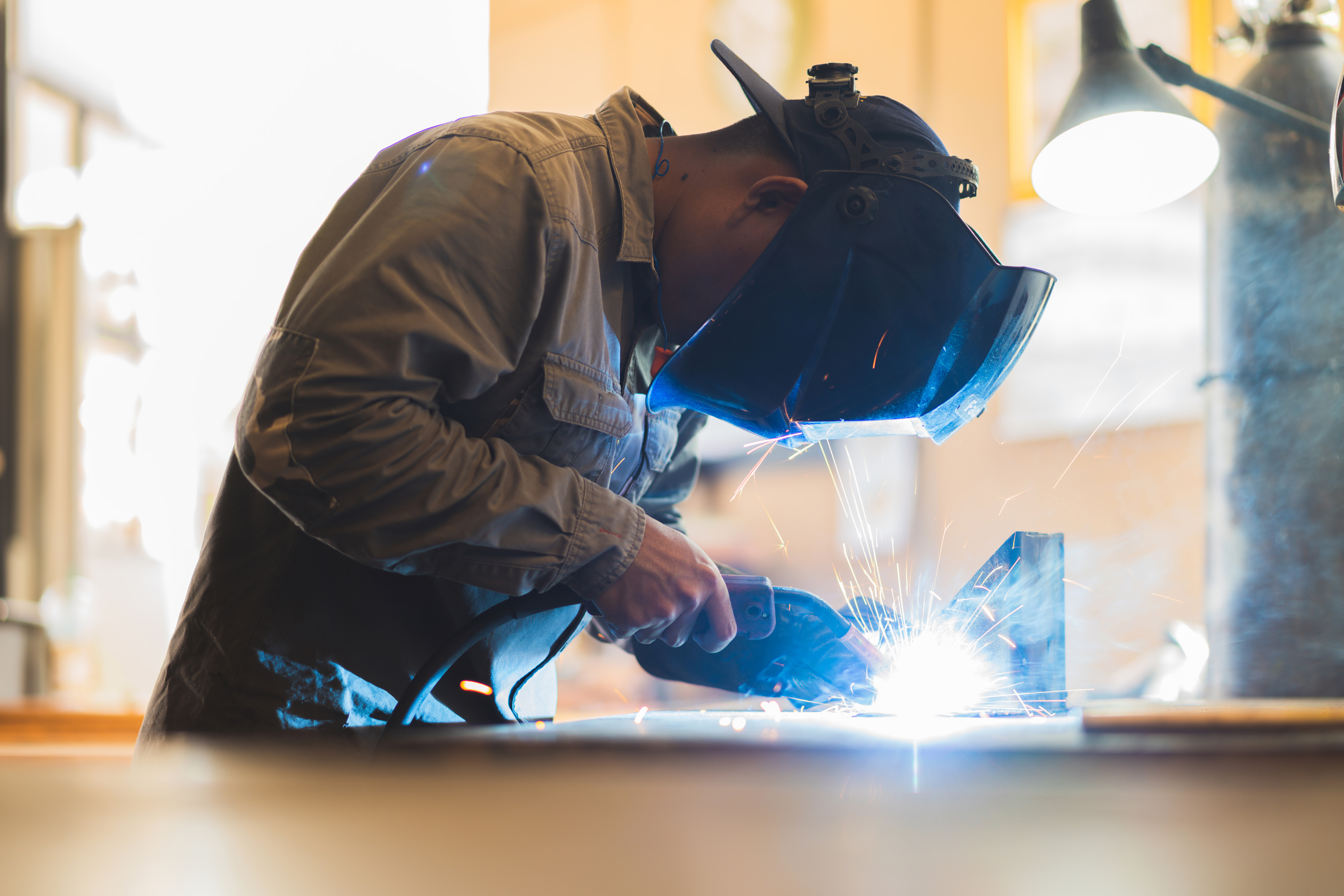 保護具を着用し、工場内の設備に溶接作業で対応する作業員の様子